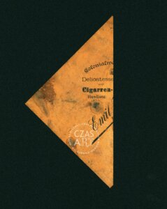 Fragment starej etykiety reklamowej lub opakowania sklepowego z przełomu XIX i XX wieku, zachowany w formie trójkątnego skrawka pożółkłego papieru. Widoczne są czarne napisy w języku niemieckim, m.in. „Colonialwaren”, „Delicatessen und Cigarren-Handlung” oraz nazwisko „Emil”, odnoszące się do właściciela sklepu. Papier nosi ślady zabrudzeń, przebarwień i zużycia. Na środku widoczny znak wodny „CZAS A.R.T.”.