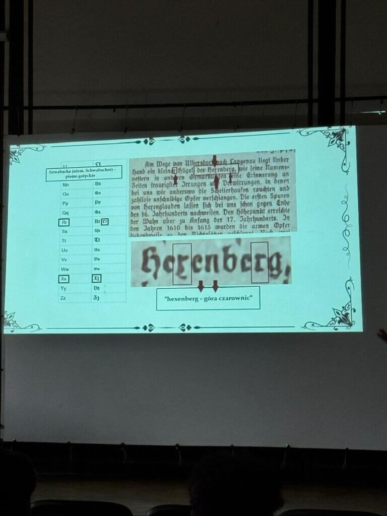 Slajd z fragmentem dokumentu historycznego i analizą słowa „Hexenberg” (góra czarownic)