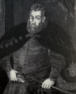 Czarnobiały portret mężczyzny w stroju szlacheckim z XVII wieku, z brodą i wąsami, trzymającego rękę na rękojeści broni. Wizerunek Hieronima Radomickiego.