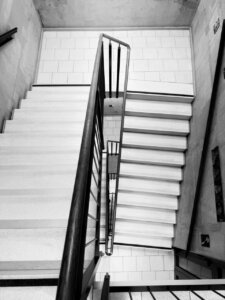 Zdjęcie czarno białe przedstawiające schody na klatce schodowej.