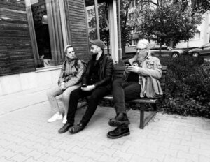 Trzy osoby siedzące na ławce. 