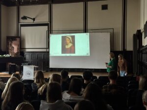 Prowadząca prezentację na tle slajdu dotyczącego procesów o czary na ziemi wschowskiej.